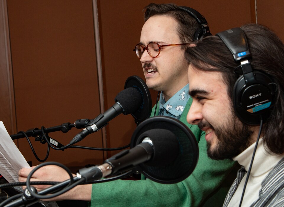 Les deux jeunes hommes sourient devant leur texte.