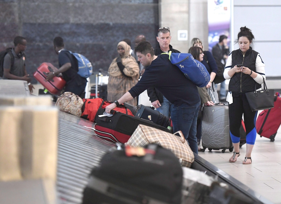Des voyageurs récupèrent leurs bagages à l'aéroport d'Ottawa, en 2017.