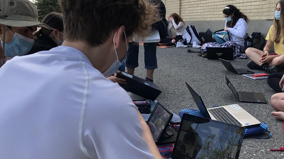 Des élèves penchés sur des tablettes et des ordinateurs portables.