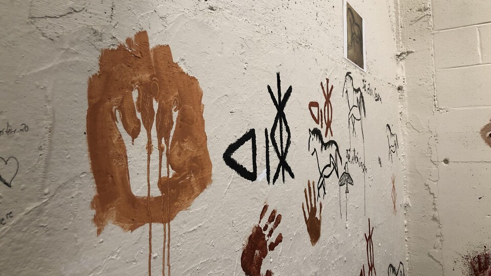 Différentes figures sont représentées sur un mur, en peinture.