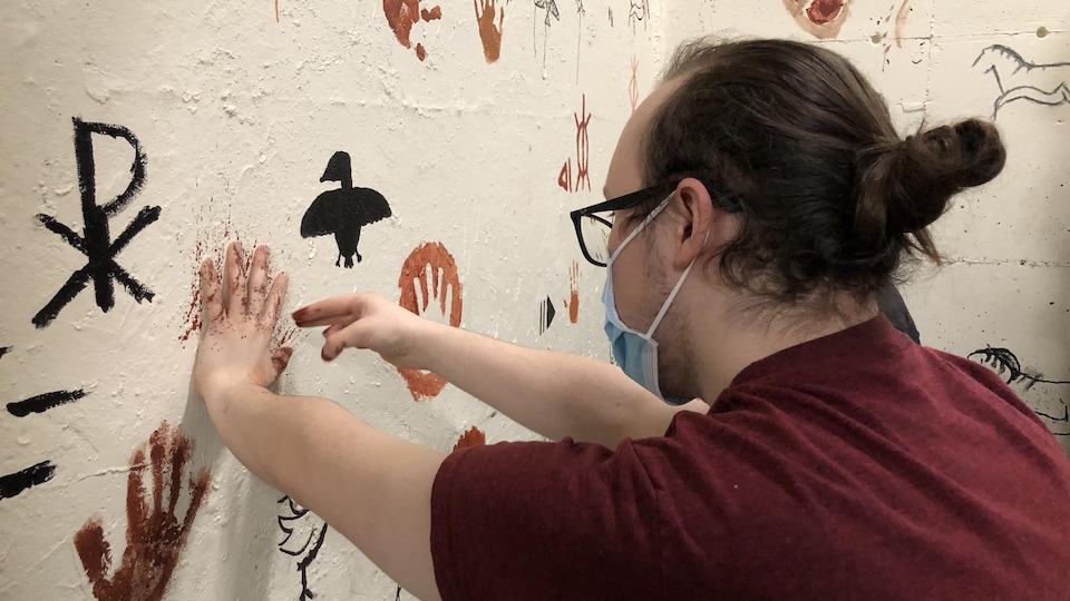 Un élève a la main appuyée au mur pour peindre autour.