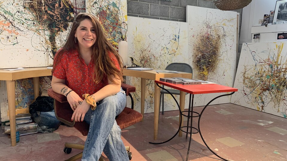 Une femme souriante assise sur une chaise dans un atelier d'artistes.