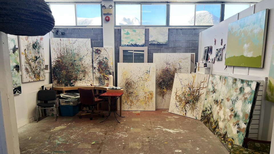 Un atelier d'artistes dans lequel se trouvent plusieurs tableaux.