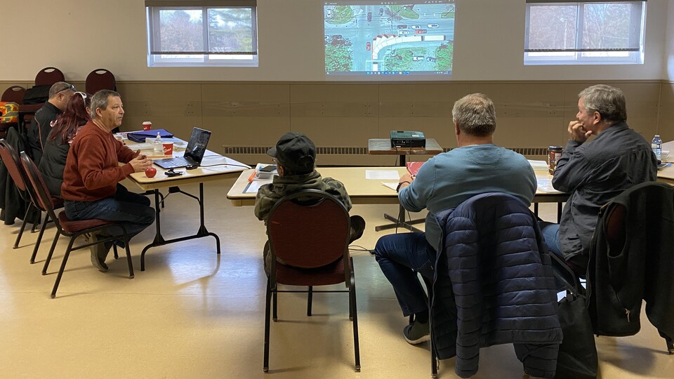 Plusieurs personnes en discussion, assises autour de tables.