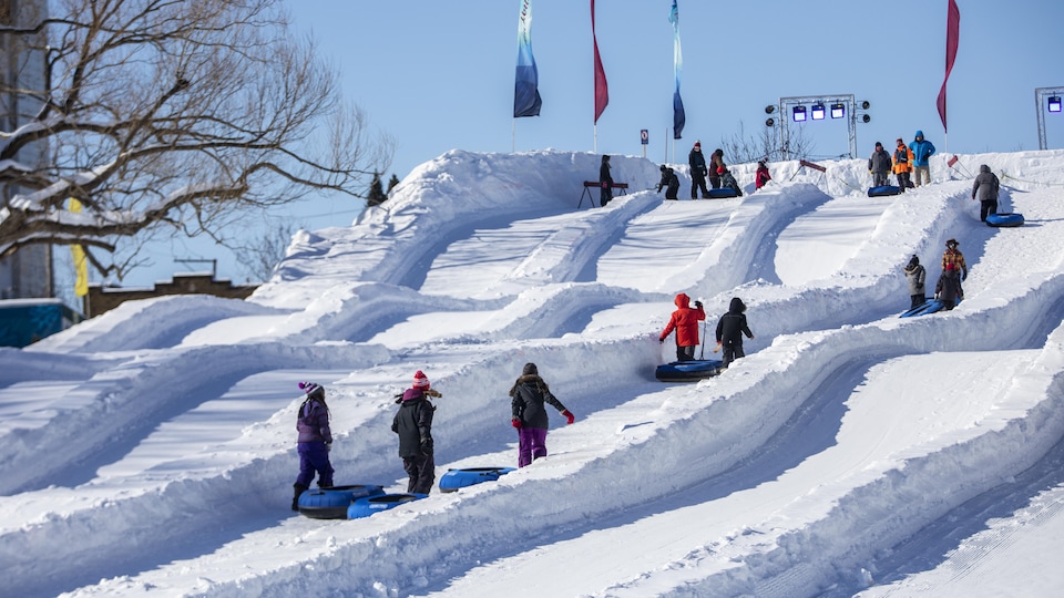 Des enfants qui glissent sur une grande montagne de neige.