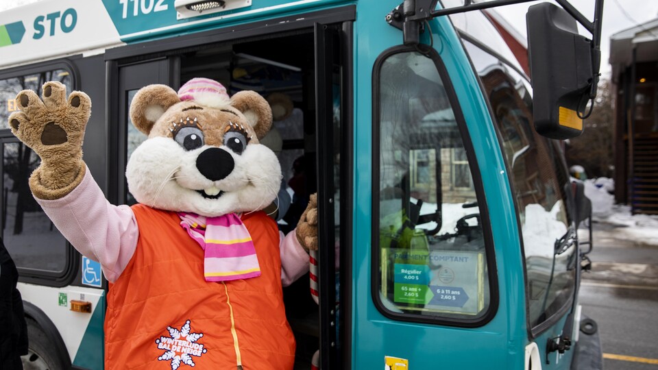 Une mascotte du Bal de neige devant un autobus de la STO.