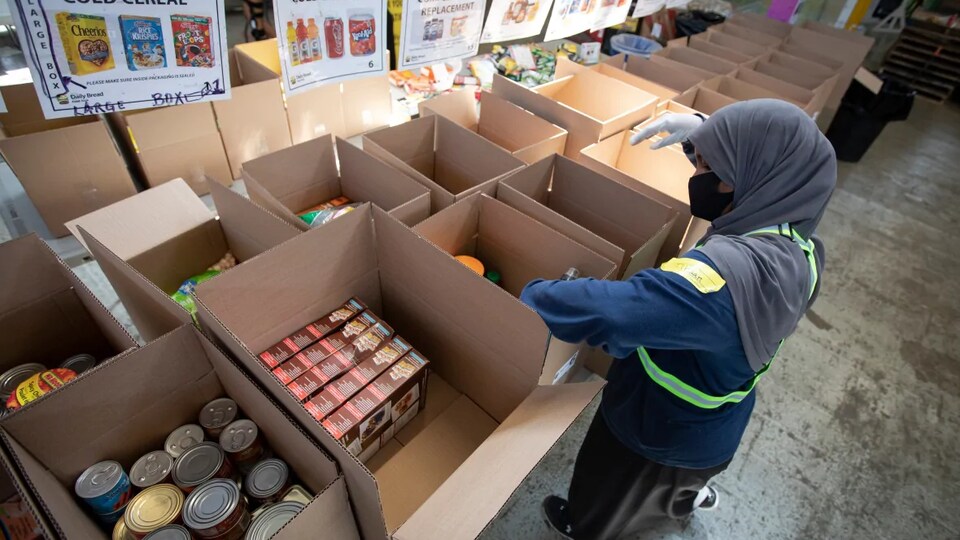 Une bénévole prépare des cartons de nourriture.