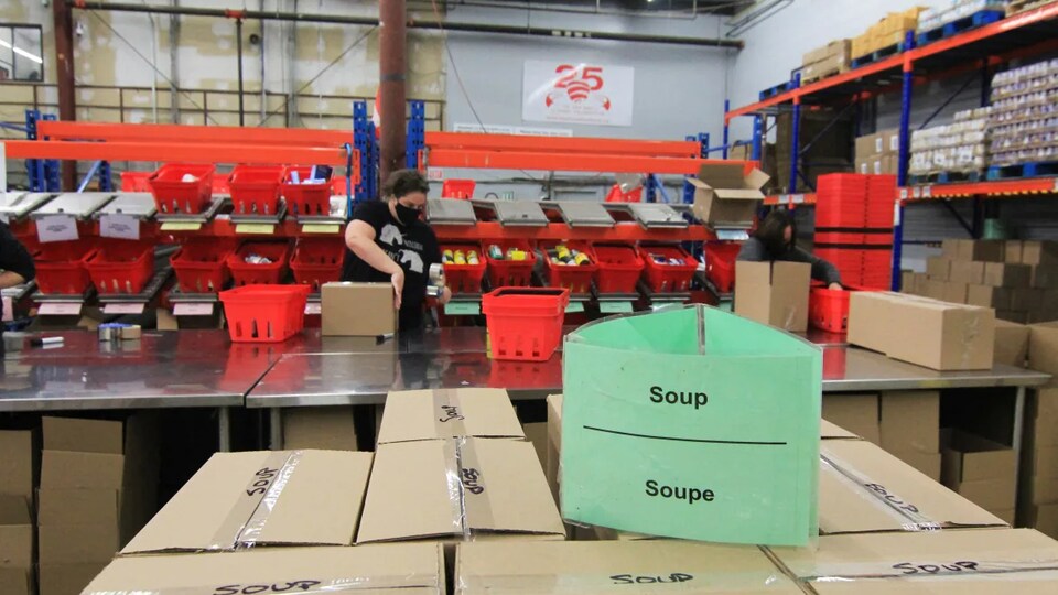 Une bénévole emballe un paquet de denrées alimentaires dans un entrepôt.