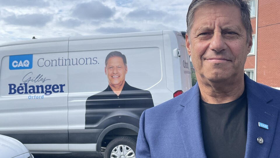 Gilles Bélanger, candidat caquiste dans Orford, devant son véhicule de campagne.