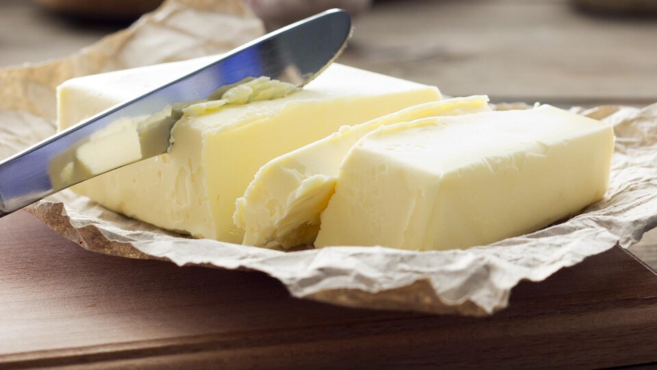 Gros plan sur une brique de beurre coupée en morceaux par un couteau.
