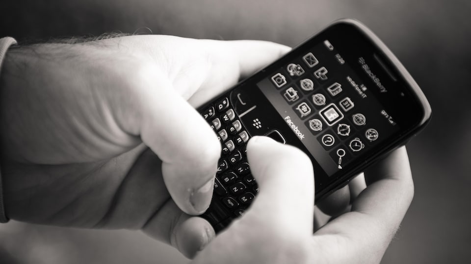 Gros plan d'une personne qui tient un appareil Blackberry dans ses mains.