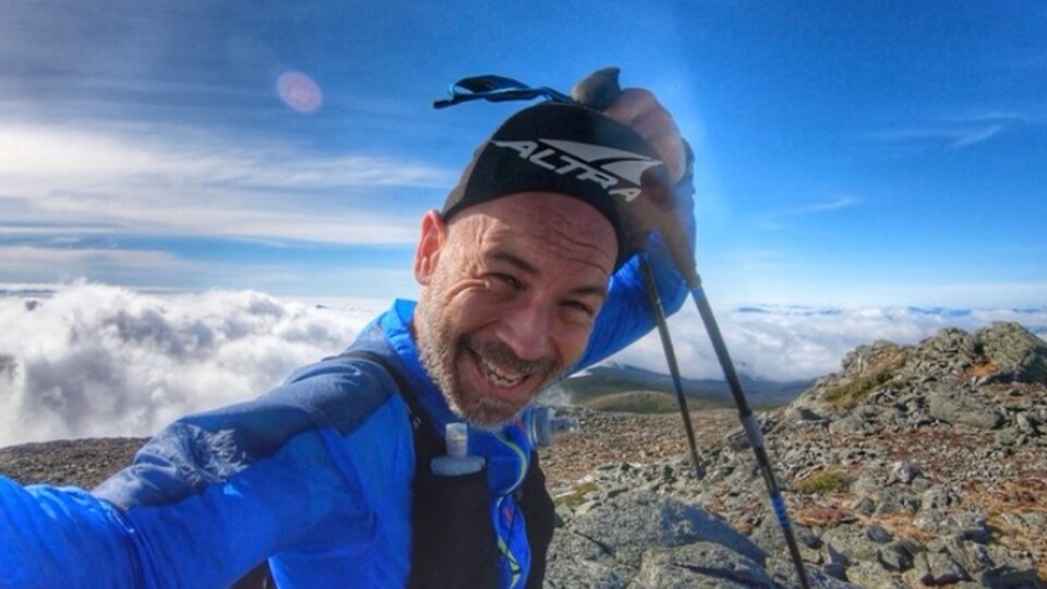 David Bombardier, souriant, au sommet d'une montagne.