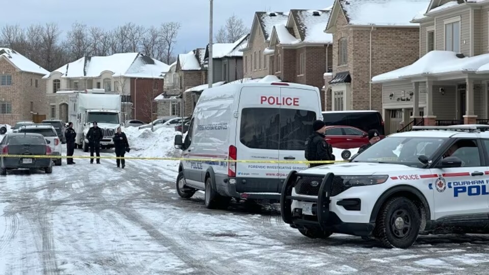 Des véhicules de police dans une rue résidentielle.
