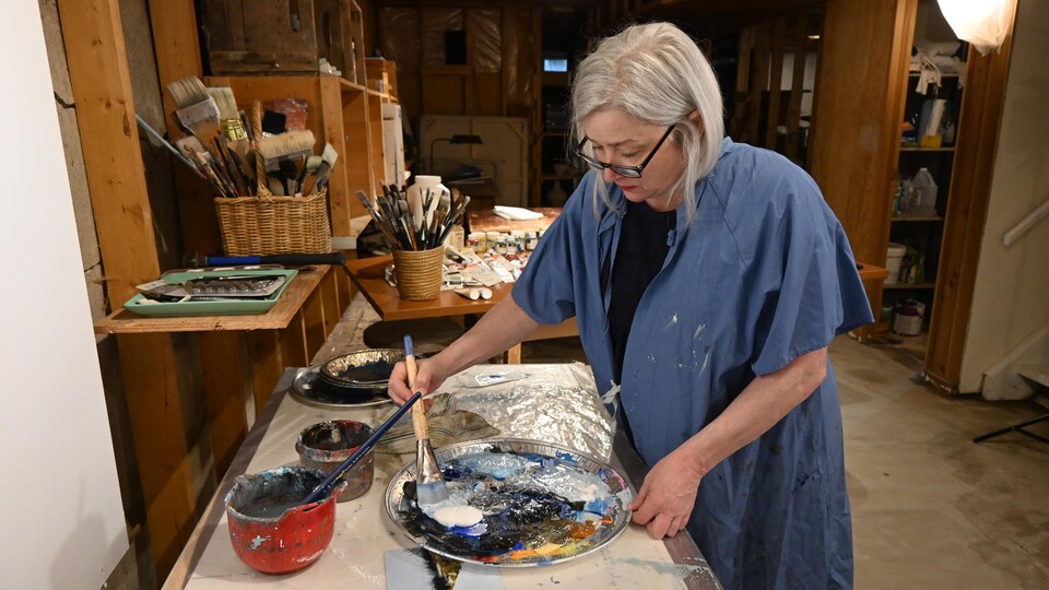 L'artiste Brigitte Dion mélange dans une assiette du blanc et du bleu.