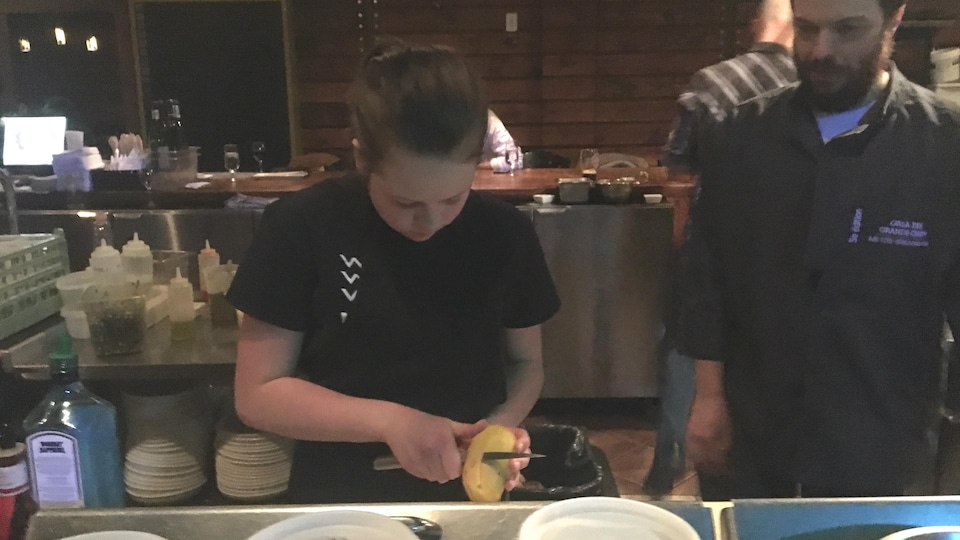Une jeune fille épluche une patate dans un restaurant.
