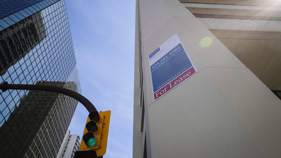 Un panneau à louer est affiché sur une tour de bureaux.