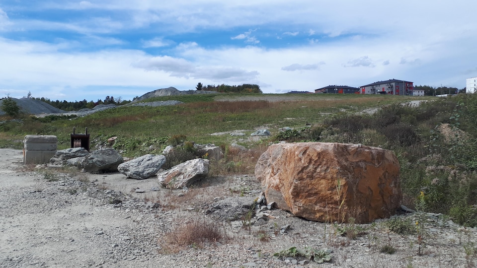 Un chantier de construction. Des maisons peuvent être vues au loin.