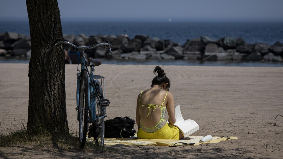 Une femme lit un livre sur une plage de Toronto.