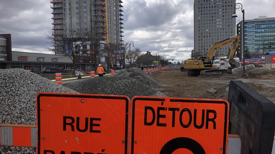 Une rue en construction derrière un panneau de rue barrée.