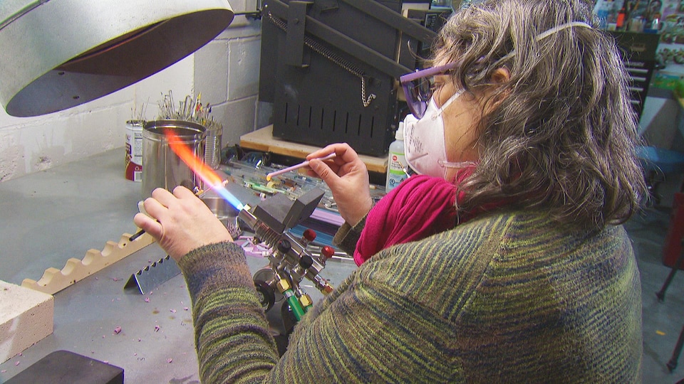Une femme en train de travailler sur une sculpture en verre soufflé dans un atelier.