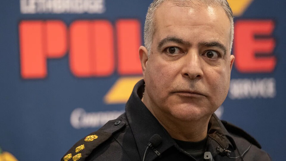 Shahin Mehdizadeh, en uniforme, devant une affiche de la police de Lethbridge.