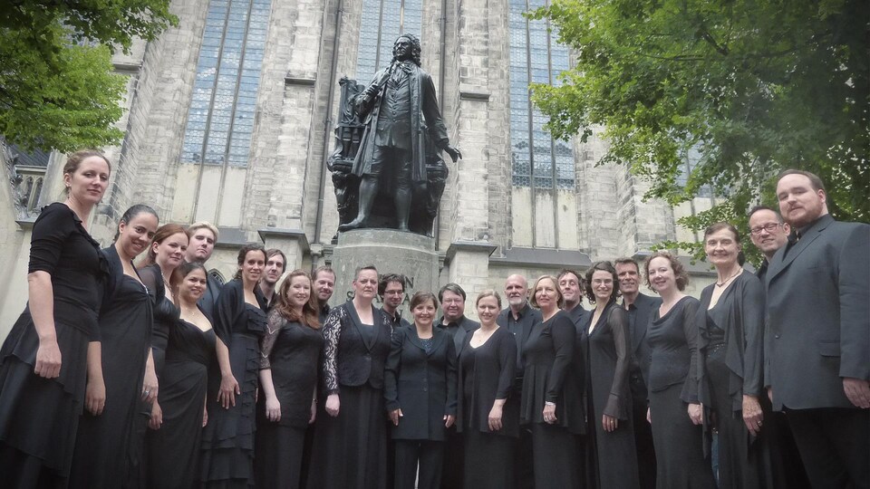 Un groupe de personnes qui posent devant une statue du compositeur Jean-Sébastien Bach.