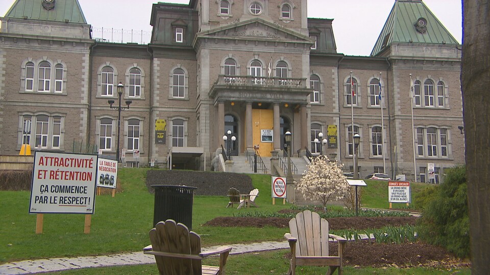 Quatre affiches sont installées devant l'hôtel de ville de Sherbrooke. La plus proche indique « Attractivité et rétention : ça commence par le respect! »