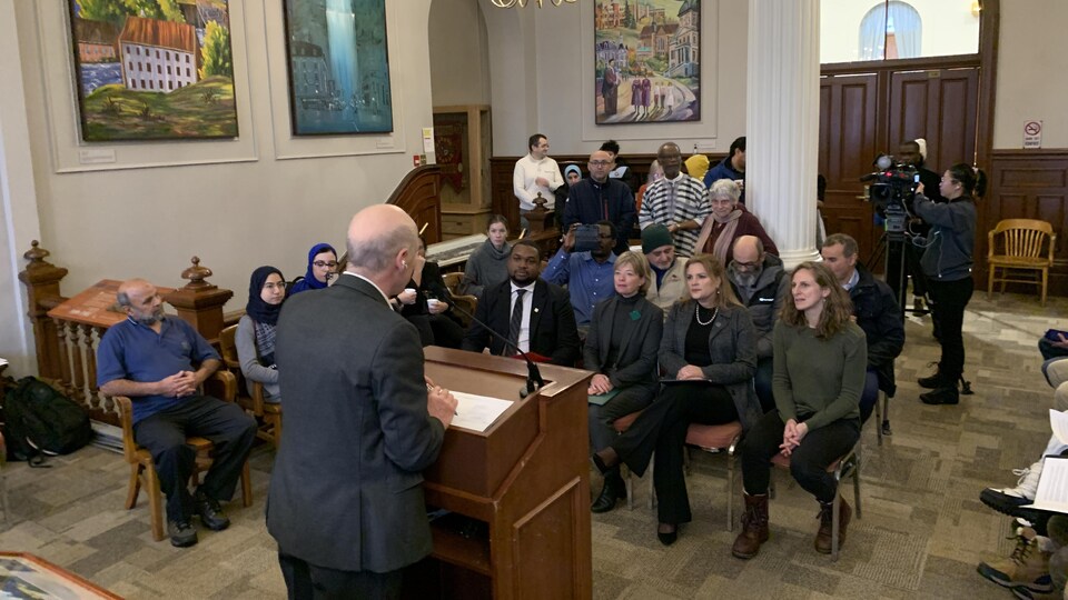 Des personnes dans une salle de l'hôtel de ville. 
