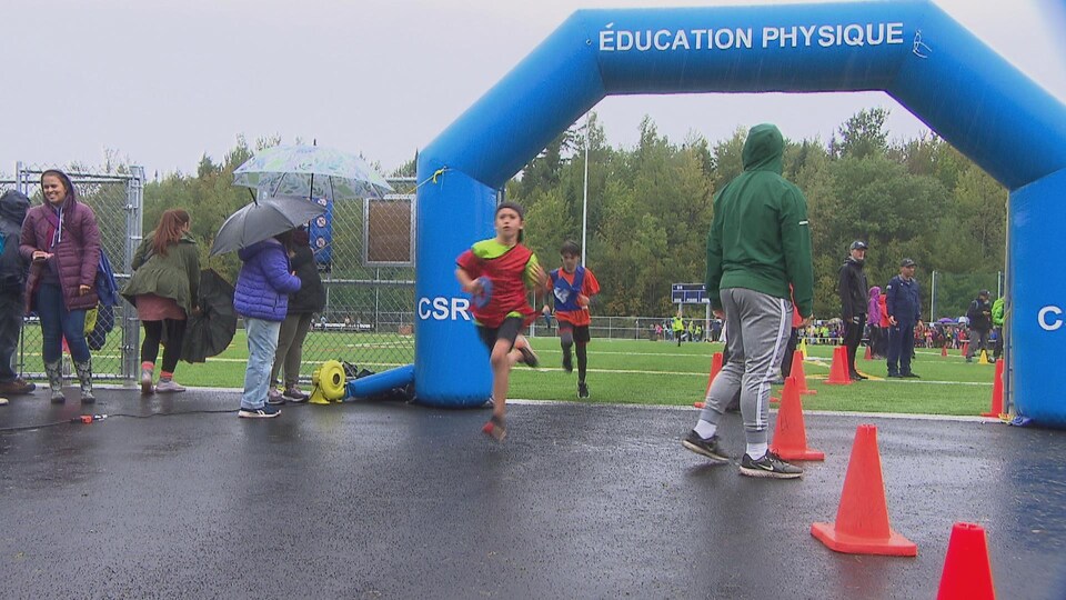 Des jeunes qui courent sous la pluie.