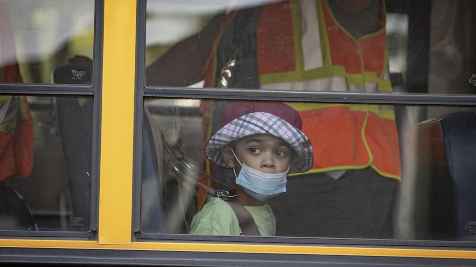 Un enfant masqué dans un autobus scolaire.