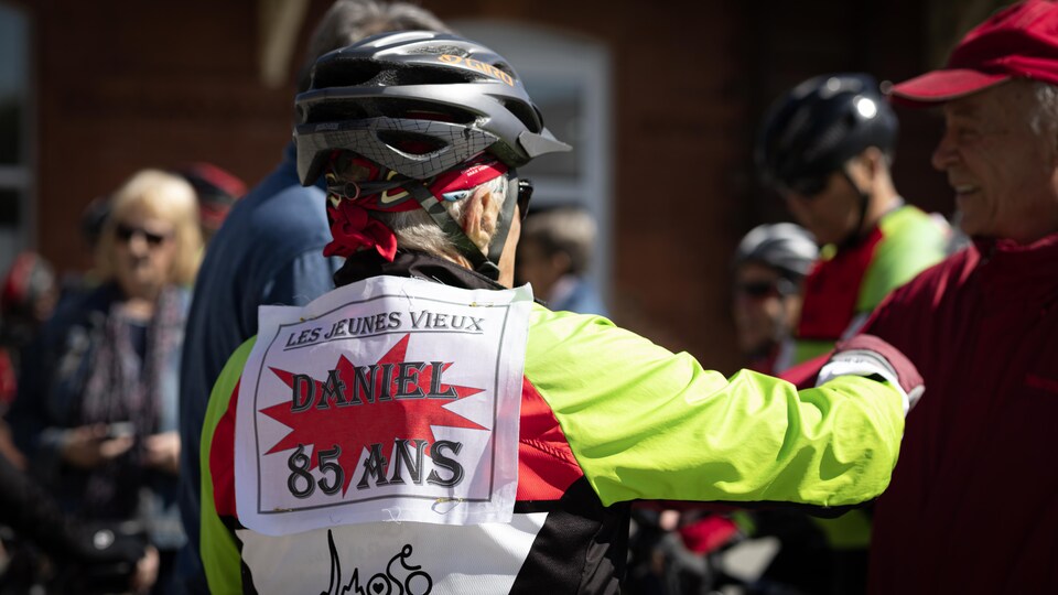 Le cycliste Daniel Roy, de dos; on peut lire sur son dossard "les jeunes vieux, Daniel 85 ans; Les Côteux de Sherbrooke".
