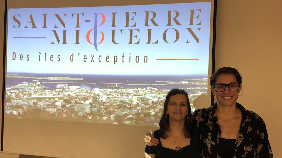 Deux femmes posent devant un écran projetant leur court métrage documentaire.