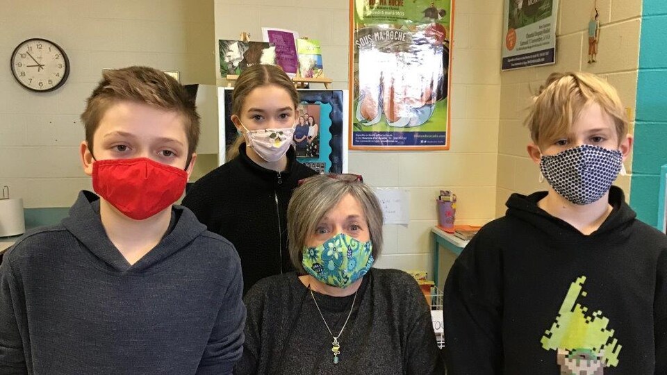 Quatre personnes regardent devant, ils portent des masques sanitaires.