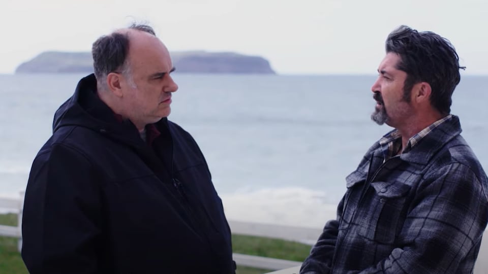 Michael Fenwick et Dwight Cornect discutent ensemble à l'extérieur devant une île, au loin.
