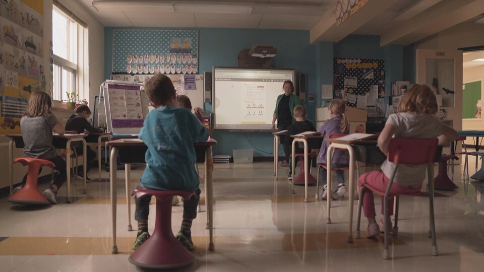 Une enseignante à l'avant d'une classe de jeunes élèves.