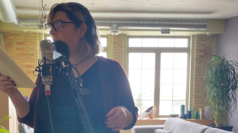 L'artiste fransaskoise éemi chante au microphone dans un salon.