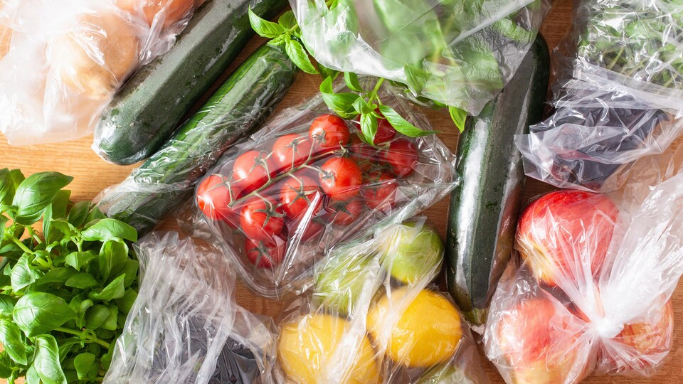 Plusieurs fruits et légumes dans des emballages de plastique.