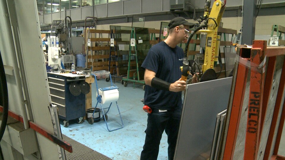 Un employé de l'entreprise Prelco déplace une pièce vitrée.