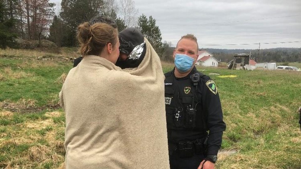 L’enfant dans les bras des parents accompagné d’un policier.