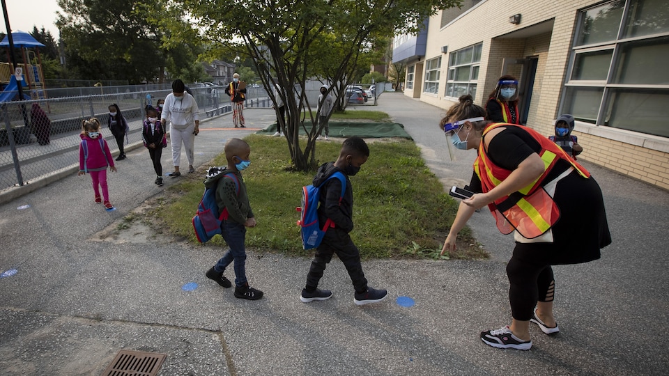 Des enfants marchent à la file dans l'enceinte d'une école de Toronto.
