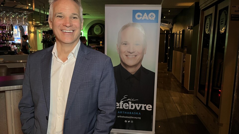 Éric Lefebvre, le candidat dans Arthabaska, tout sourire devant une pancarte.