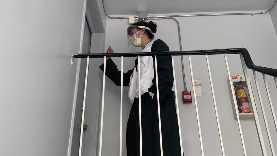 Une étudiante frappe à la porte d'un appartement dans le cadre de son travail de sensibilisation.