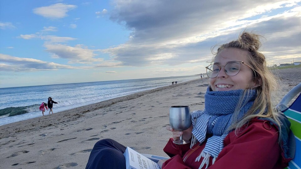 La journaliste est assise avec un libre à la plage.