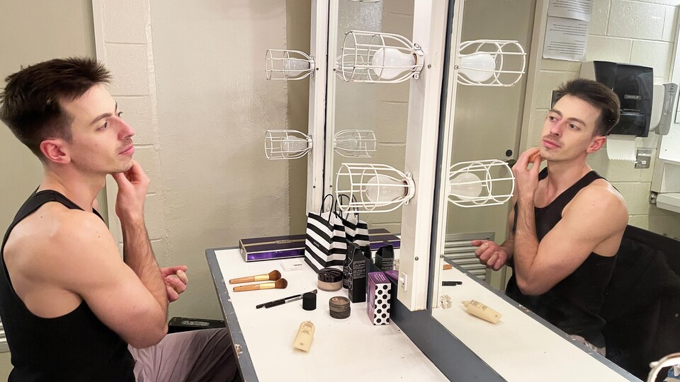 Étienne Gagnon-Delorme en train de se maquiller devant un grand miroir.