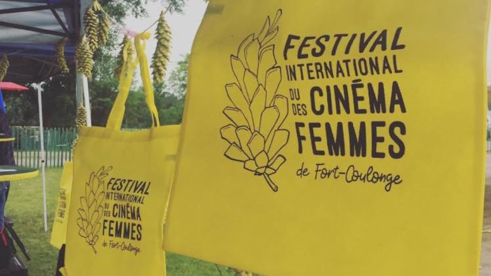 Des sacs avec un logo du Festival international du Cinéma des Femmes de Fort-Coulonge sont accrochés à une corde à linge.
