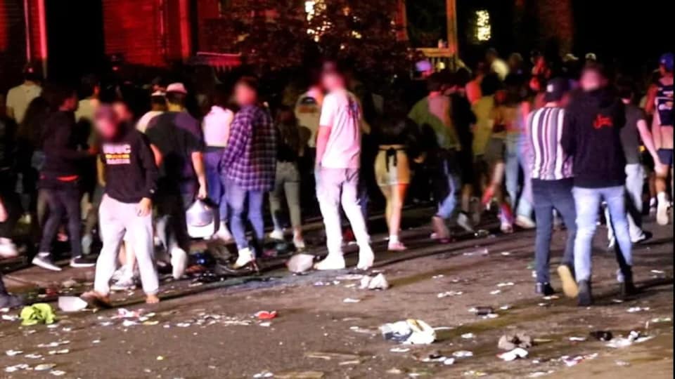 Des personnes rassemblées dans une rue, des détritus par terre.