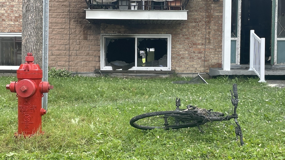 Un vélo électrique brûlée devant un immeuble à logements.