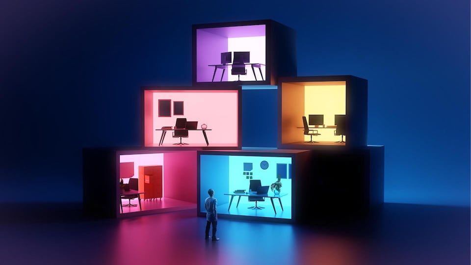 Un homme debout qui regarde plusieurs espaces de travail dans des cubes qui sont placés les uns sur les autres.