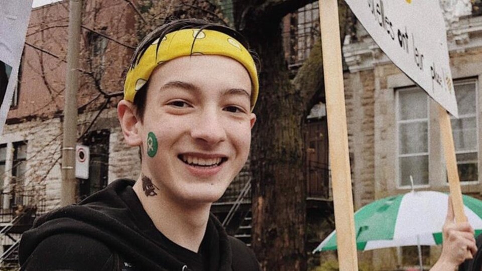 Anthony Duval, souriant, qui tient une pancarte lors d'une manifestation.