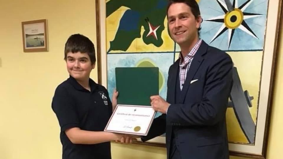 Un jeune garçon reçoit un certificat d'un homme en lui serrant la main.